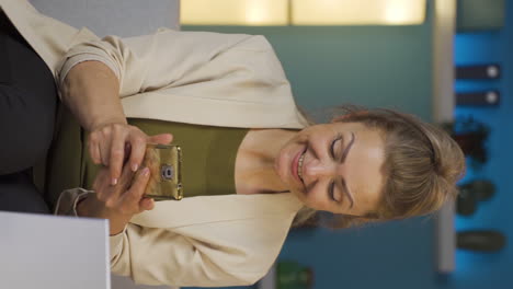 Vertical-video-of-Home-office-worker-woman-getting-good-news-on-the-phone.